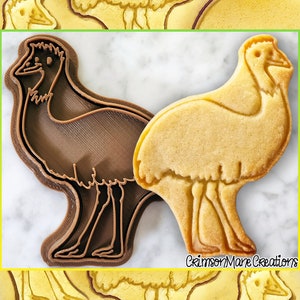 Peut inclure: Un emporte-pièce en plastique brun en forme d'émeu, à côté d'un biscuit au sucre cuit en forme d'émeu. L'emporte-pièce est sur une surface en marbre blanc. Le biscuit est brun clair et a un contour brun légèrement plus foncé. Le texte "Crimson Mare Creations" est visible dans le coin inférieur droit de l'image.