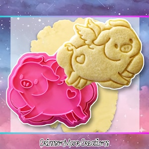 May include: A pink pig-shaped cookie cutter alongside a baked cookie in the same shape. The cookie has wings and a heart. The cookie cutter is made of plastic. The text "Crimson Mane Creations" is at the bottom.