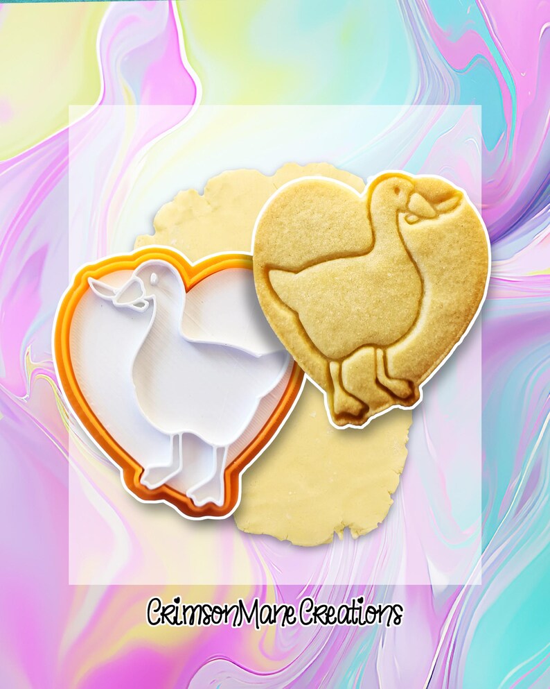 May include: A heart-shaped cookie cutter and a baked cookie, both featuring a goose design. The cookie cutter is white with an orange border. The baked cookie is golden brown and sits on a piece of dough. The text "Crimson Mane Creations" is visible.
