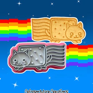 May include: Two cookie cutters in the shape of a Nyan Cat, one tan and one gray, with a rainbow and a blue background. The tan cutter is a cookie with a cat face and a pop-tart body. The gray cutter has a pink outline.