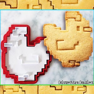 May include: A red plastic cookie cutter shaped like a pixelated heart, with a white cookie inside the cutter. The cookie is also pixelated and has a heart shape. The text "Crimson Mare Creations" is visible in the bottom right corner of the image.