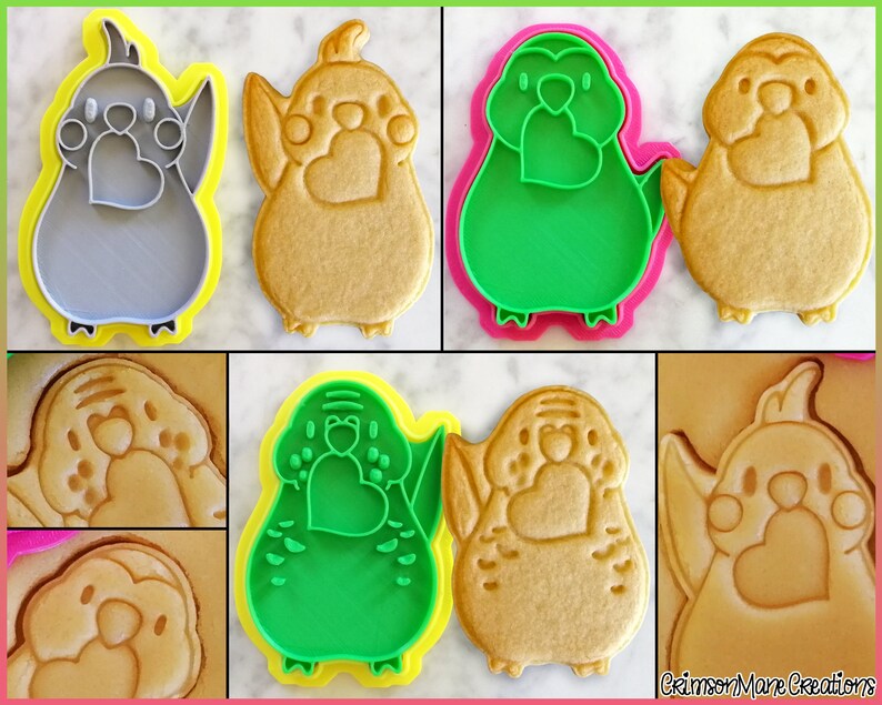 May include: A set of four cookie cutters in the shape of a parakeet holding a heart. Two cutters are green, one is gray, and one is brown. The cutters are on a white surface.