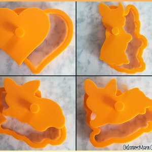 May include: A set of four bright orange plastic cookie cutters featuring a heart shape and three distinct rabbit silhouettes. Each cutter consists of a frame and a matching plunger top with a central handle for pressing dough into shapes.