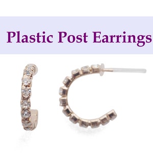 Może przedstawiać: Dwa kolczyki koła z przezroczystymi cyrkoniami osadzonymi w metalu w kolorze złota. Kolczyki mają kształt półkola. Tekst "Plastic Post Earrings" znajduje się powyżej.