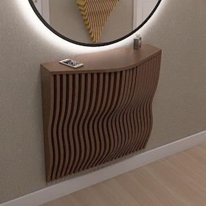 May include: A modern wooden console table with a wavy design and a built-in shelf. The table is illuminated by a round mirror with a halo of light. The mirror reflects a small entryway with a decorative shelf and two wall sconces.