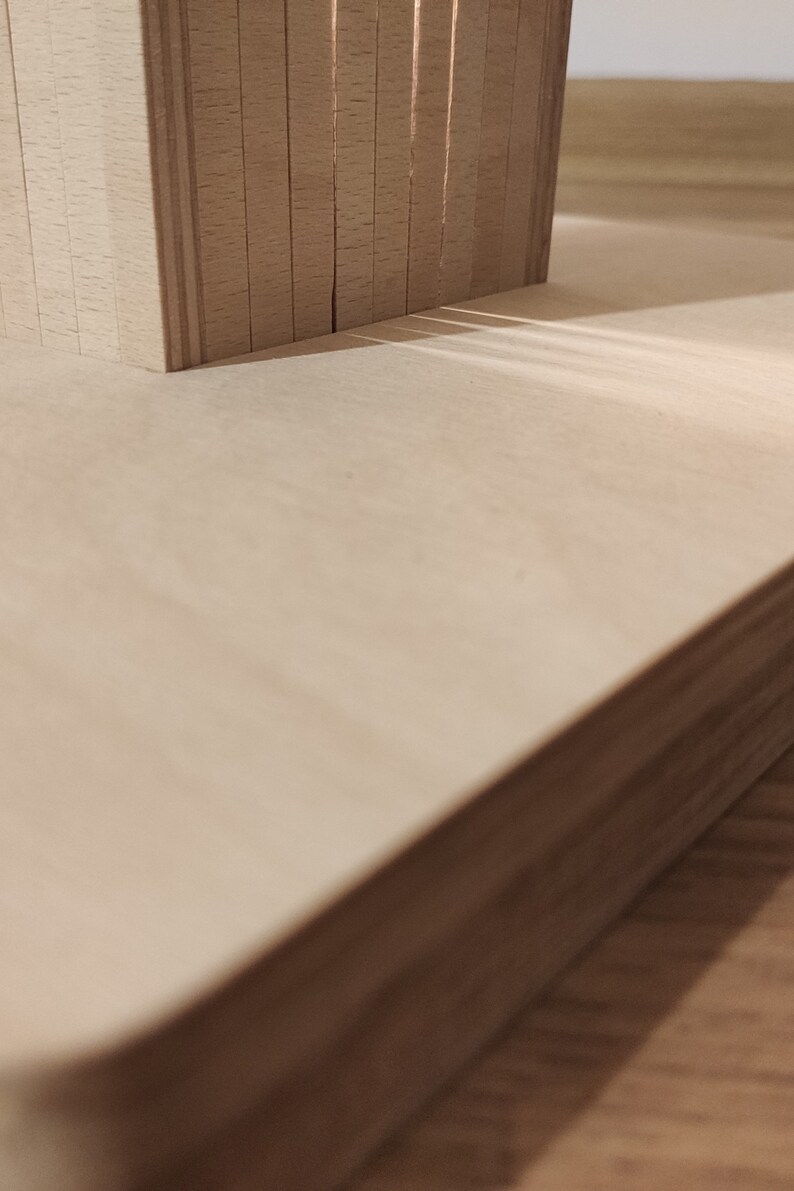May include: Close-up of a light-colored wooden surface with a stack of thin, vertical wooden pieces. The wood has a natural grain and texture. The image is well-lit, highlighting the details of the wood.