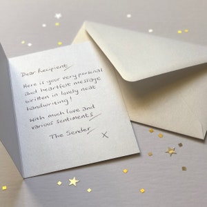 May include: An open greeting card with handwritten text, an envelope, and scattered gold confetti. The card reads "Dear Recipient, Here is your very personal and heartfelt message written in lovely neat handwriting! With much love and various sentiments, The Sender X."