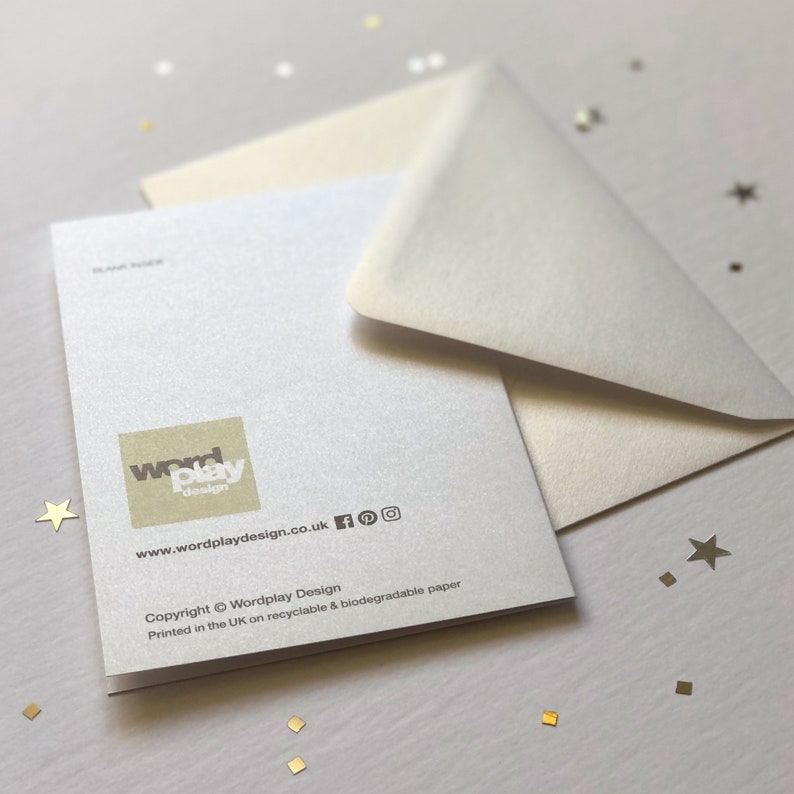 May include: A blank greeting card with a matching envelope. The card has a pearlescent finish and the Wordplay Design logo in the lower left corner. The website address and social media icons are visible. The card is printed on recyclable and biodegradable paper.