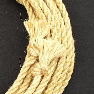 K&ouml;nnte beinhalten: Nahaufnahme eines dicken, nat&uuml;rlichen Faserseils mit einem verknoteten Ende. Das Seil besteht aus mehreren miteinander verdrehten Str&auml;ngen und hat eine nat&uuml;rliche, beige Farbe.