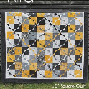 May include: A geometric quilt with a black border, featuring squares and triangles in yellow, black, gray, and white. The quilt is labeled "Kira" and is a "10" Square Quilt". The dimensions are 97" x 114".