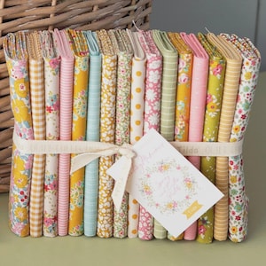 May include: A stack of folded fabric pieces in various patterns including floral, gingham, and stripes, featuring yellow, pink, green, and blue colors. The fabric bundle is tied with a cream ribbon and a white tag with floral graphics and text.