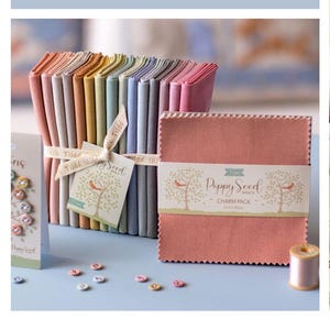 May include: A Tilda Poppy Seed Basics charm pack of square fabric pieces with pinked edges, bundled with a stack of folded fabric in various pastel colors. A tag features a tree illustration and the text Poppy Seed Basics Charm Pack 5x5in.