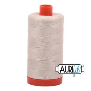 May include: A spool of off-white sewing thread with a red top and base. The thread is tightly wound, and the spool has the Aurifil logo on the side. This thread is likely used for quilting, embroidery, or general sewing projects.