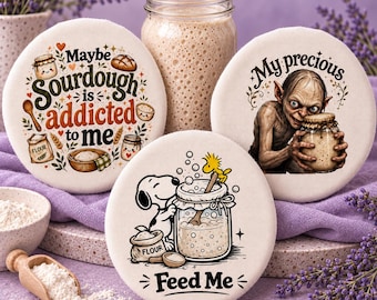 May include: Three round fabric bowl covers featuring printed illustrations. One reads 'Maybe Sourdough is addicted to me' with baking icons. Another shows a creature holding a jar with 'My precious'. The third shows a dog with 'Feed Me'.