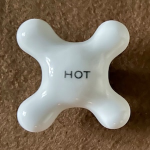 May include: White ceramic hot water faucet knob with the word "HOT" printed on the top.
