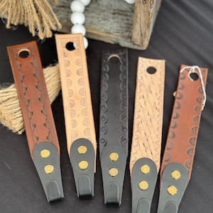 May include: Six leather straps with different embossed designs and black metal tips. Each strap has three brass rivets.
