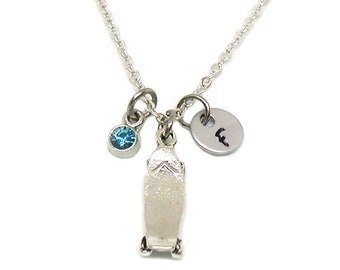 May include: Silver necklace with a skateboard charm, a blue gemstone, and a silver charm with the letter "F" engraved on it.