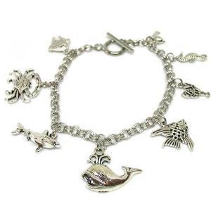 May include: Silver charm bracelet with a variety of sea creature charms, including a whale, dolphin, crab, seahorse, and fish.