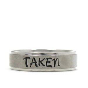 May include: A silver ring with the word "TAKEN" engraved on it.