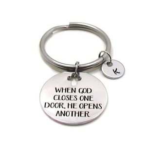 May include: Silver keychain with a round charm that reads "When God closes one door, He opens another".