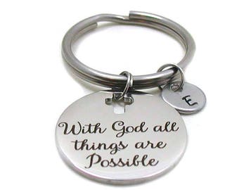 May include: Silver keychain with a round charm that says "With God all things are Possible". The charm has a small cross engraved on it. The keychain also has a small silver charm with the letter "E" engraved on it.