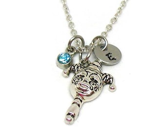 May include: A silver necklace with a jester charm, a small blue crystal, and a silver disc with the letter "K" engraved on it.