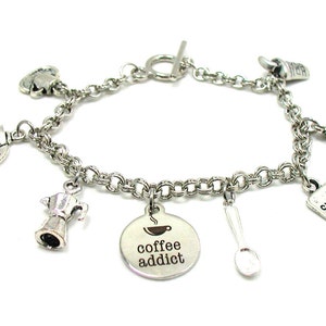 May include: Silver charm bracelet with coffee themed charms, including a coffee pot, a coffee cup, a sugar packet, and a spoon. The charm bracelet also includes a round charm with the text "coffee addict".