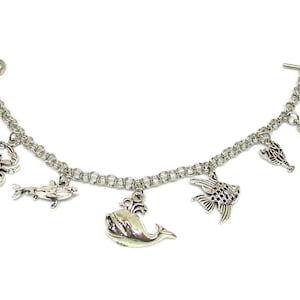 May include: A silver charm bracelet with a variety of sea creature charms, including a whale, a crab, a seahorse, and fish.