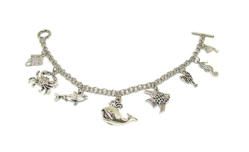May include: A silver charm bracelet with a variety of sea creature charms, including a whale, a crab, a seahorse, and fish.
