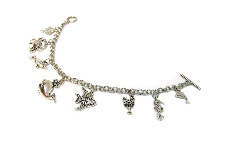 May include: A silver charm bracelet with a variety of sea creature charms, including a whale, a fish, a crab, a lobster, a seahorse, and a dolphin.
