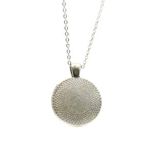 May include: Silver necklace with a round pendant featuring a detailed, circular design.