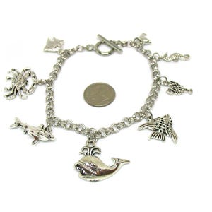 May include: Silver charm bracelet with a variety of sea creature charms, including a whale, dolphin, crab, seahorse, and fish.