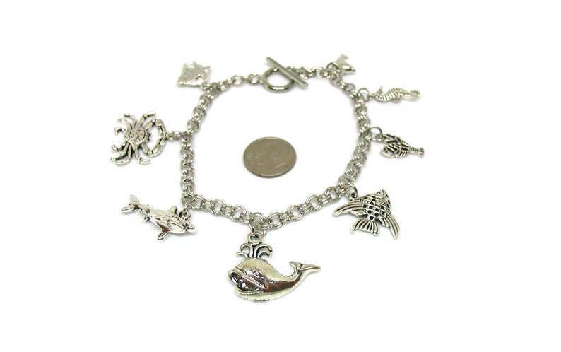 May include: Silver charm bracelet with a variety of sea creature charms, including a whale, dolphin, crab, seahorse, and fish.