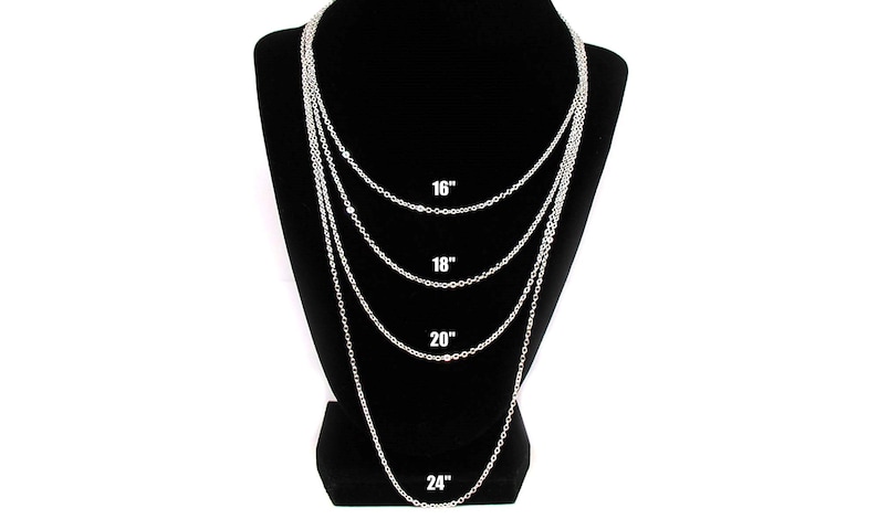 Puede incluir: Cuatro cadenas plateadas de diferentes longitudes mostradas en un maniqu&iacute; negro. Las cadenas miden 40,6 cm, 45,7 cm, 50,8 cm y 61 cm de largo.