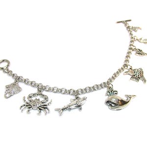 May include: Silver charm bracelet with various sea creature charms, including a crab, a whale, a shark, a starfish, and a seahorse.
