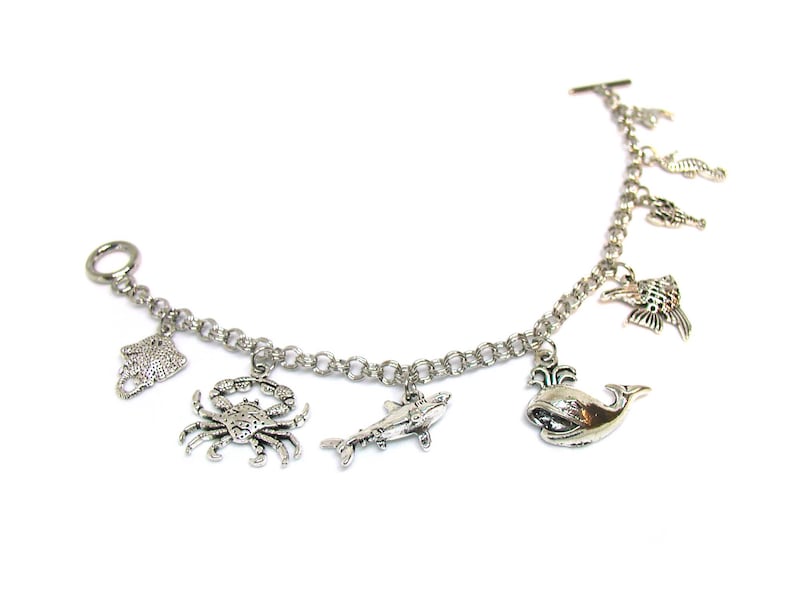 May include: Silver charm bracelet with various sea creature charms, including a crab, a whale, a shark, a starfish, and a seahorse.