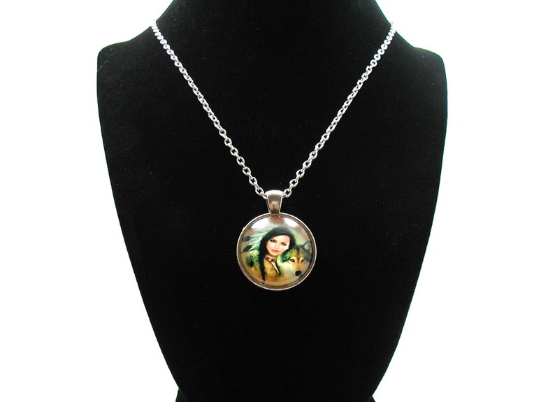 May include: A silver chain necklace with a round glass pendant featuring a woman with a wolf. The pendant has a silver border and the image is of a woman with long dark hair and a wolf with brown fur.
