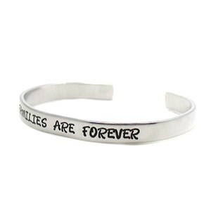 Peut inclure: Un bracelet jonc en argent avec l'inscription "Families are forever".
