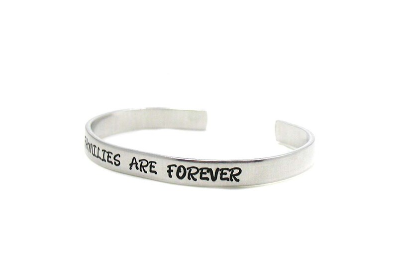 Peut inclure: Un bracelet jonc en argent avec l'inscription "Families are forever".