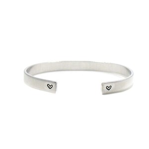Peut inclure: Un bracelet jonc en argent avec deux petites gravures en forme de c&oelig;ur.