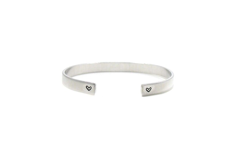 Peut inclure: Un bracelet jonc en argent avec deux petites gravures en forme de c&oelig;ur.