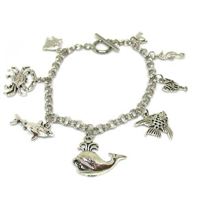 May include: Silver charm bracelet with a variety of sea creature charms, including a whale, dolphin, crab, seahorse, and fish.
