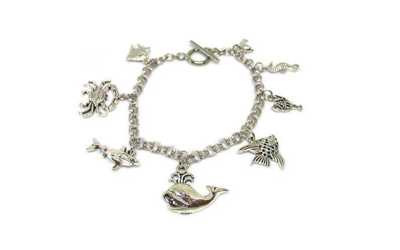 May include: Silver charm bracelet with a variety of sea creature charms, including a whale, dolphin, crab, seahorse, and fish.