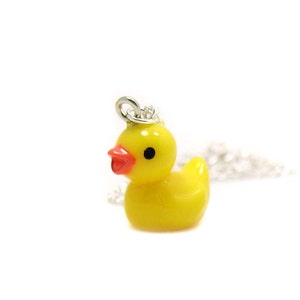May include: A yellow rubber ducky charm on a silver chain necklace. The ducky has a red beak and black eyes.