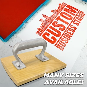 May include: A custom business stamp with a wooden base and a silver handle. The stamp is shown with a red ink pad and a printed example in red ink. The text "CUSTOM BUSINESS STAMP" is visible, along with "MANY SIZES AVAILABLE!"