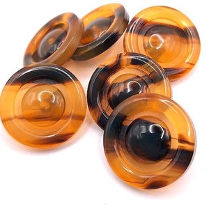 May include: Six brown and black tortoise shell buttons with a concentric circle design.
