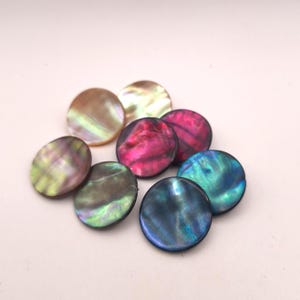 Puede incluir: Una colección de cuentas redondas e iridiscentes de concha en varios colores. Las cuentas muestran una gama de tonos, incluyendo rosa, azul, verde y dorado, con un acabado brillante y nacarado. Estas cuentas decorativas son ideales para la fabricación de joyas y proyectos de artesanía.