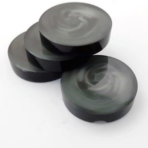 May include: Four black and white swirl coasters. The coasters are round and have a glossy finish.