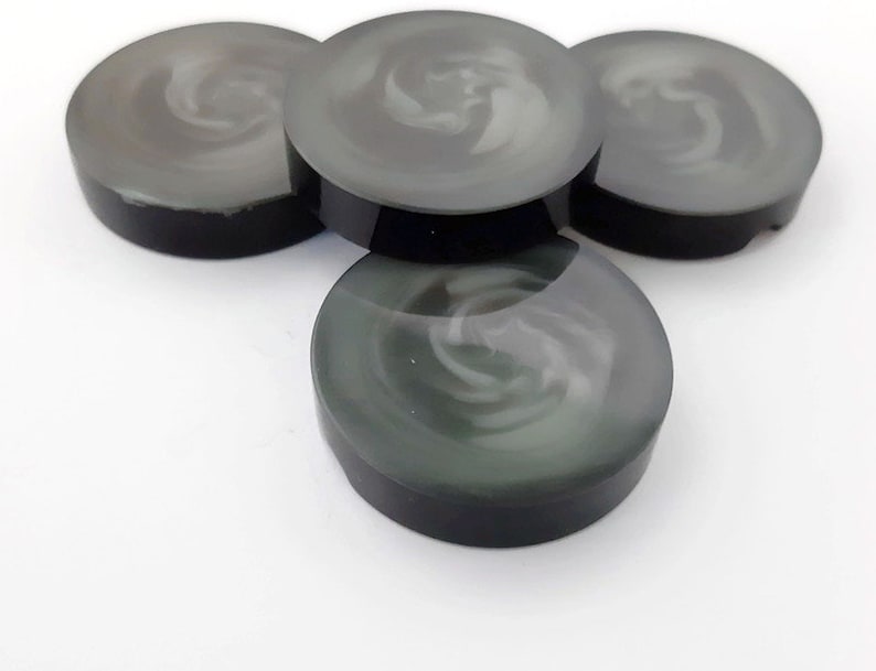 May include: Four black and white swirl design round buttons. The buttons are made of a smooth, glossy material.