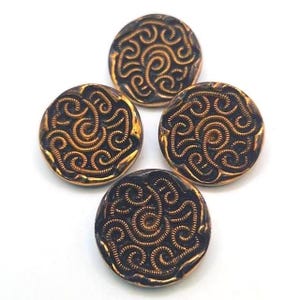 May include: Four round buttons with a dark brown base and a gold-colored, swirling design. The buttons have a metallic sheen and a raised pattern. The buttons are likely for sewing or crafts.